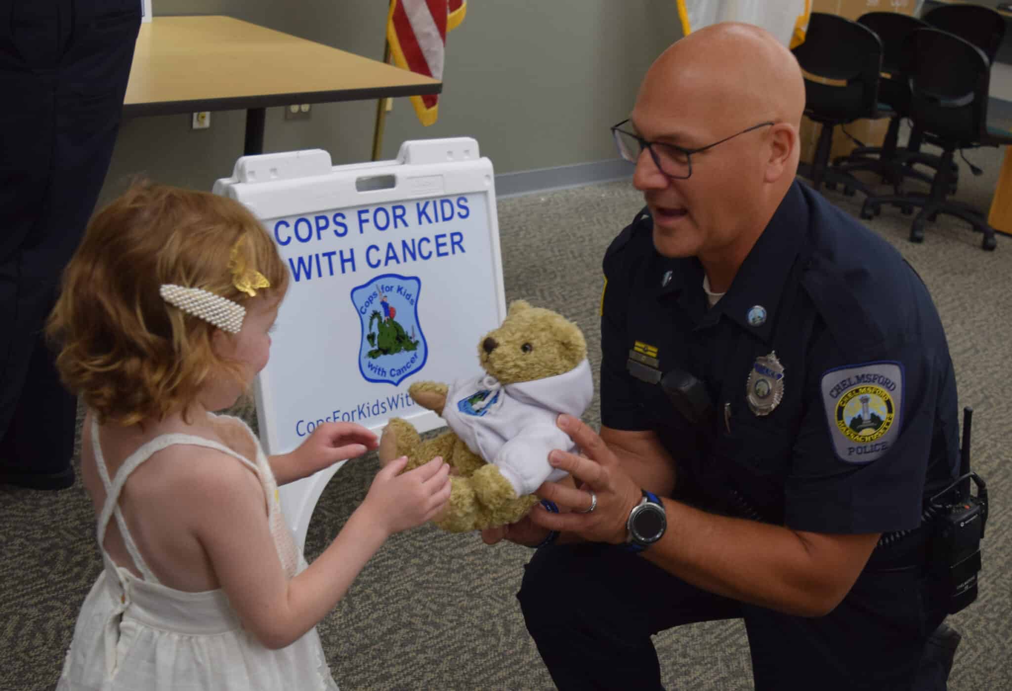 A board member gives a young girl a stuffed teddy bear.