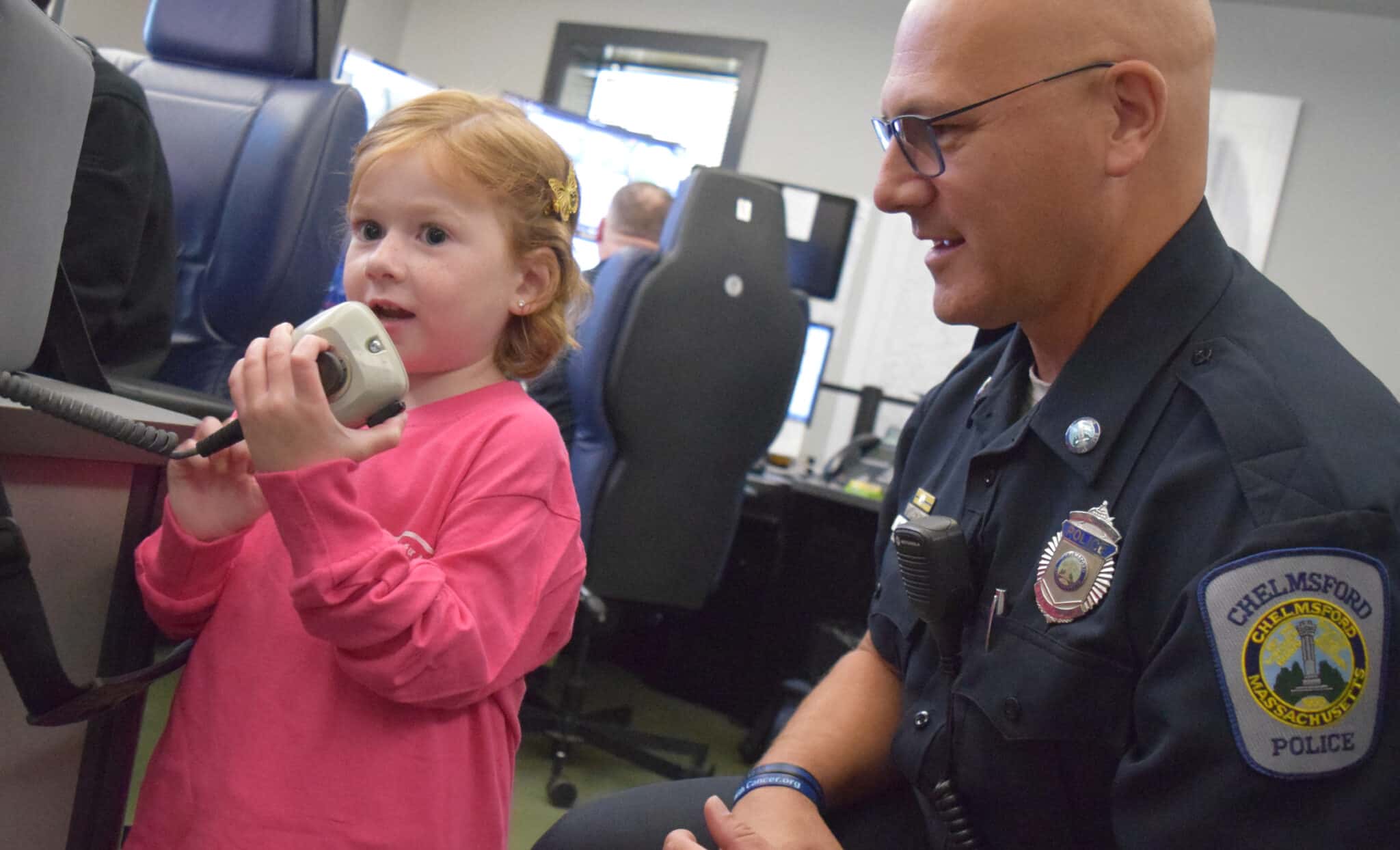 Cops for Kids with Cancer Board Member and Special Traffic Officer Sal Mirabella, Jr., watches as 5-year-old Carson Doherty radios to an on-duty Chelmsford Police officer in the field during a tour of the station. "I hope you have a nice day," Carson said after contacting the officer via radio.