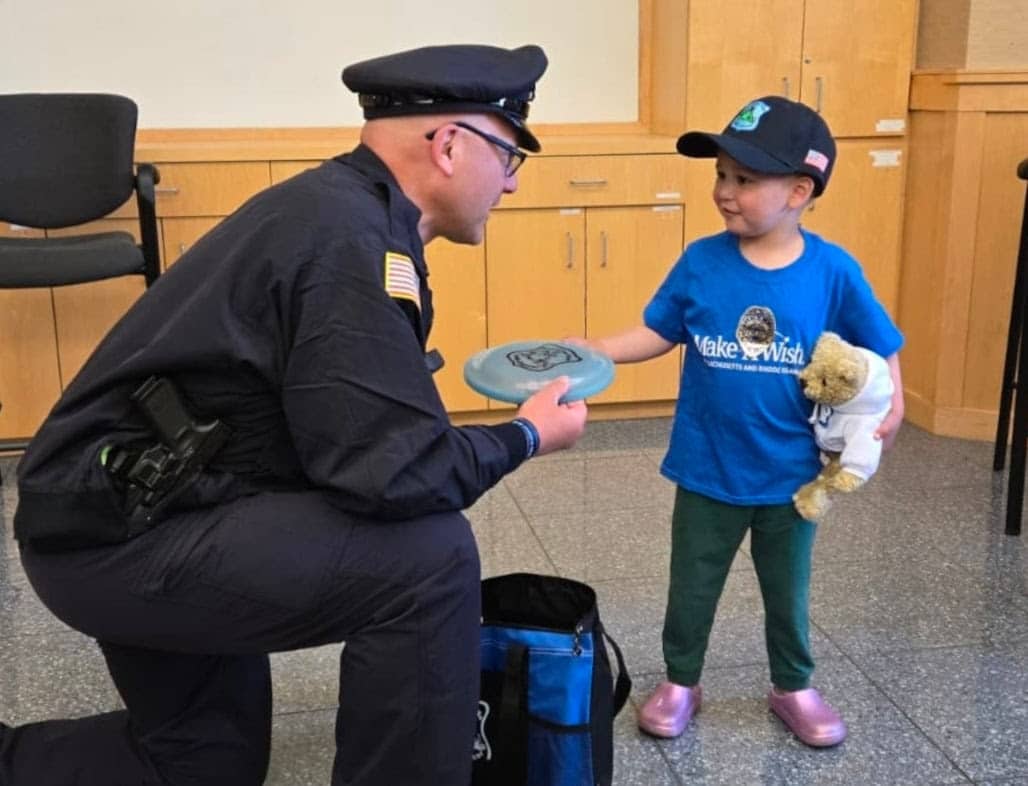 Henry Costigan, 3, accepts a teddy bear and frisbee from Cops for Kids with Cancer Board Member Sal Mirabella, Jr., last month at the Acton Police Department. Cops for Kids with Cancer and Acton Police provided Henry and his family with ,500 to support their ongoing battle with cancer.